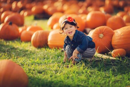Little girl sitting around pumpkins is Thanksgiving time